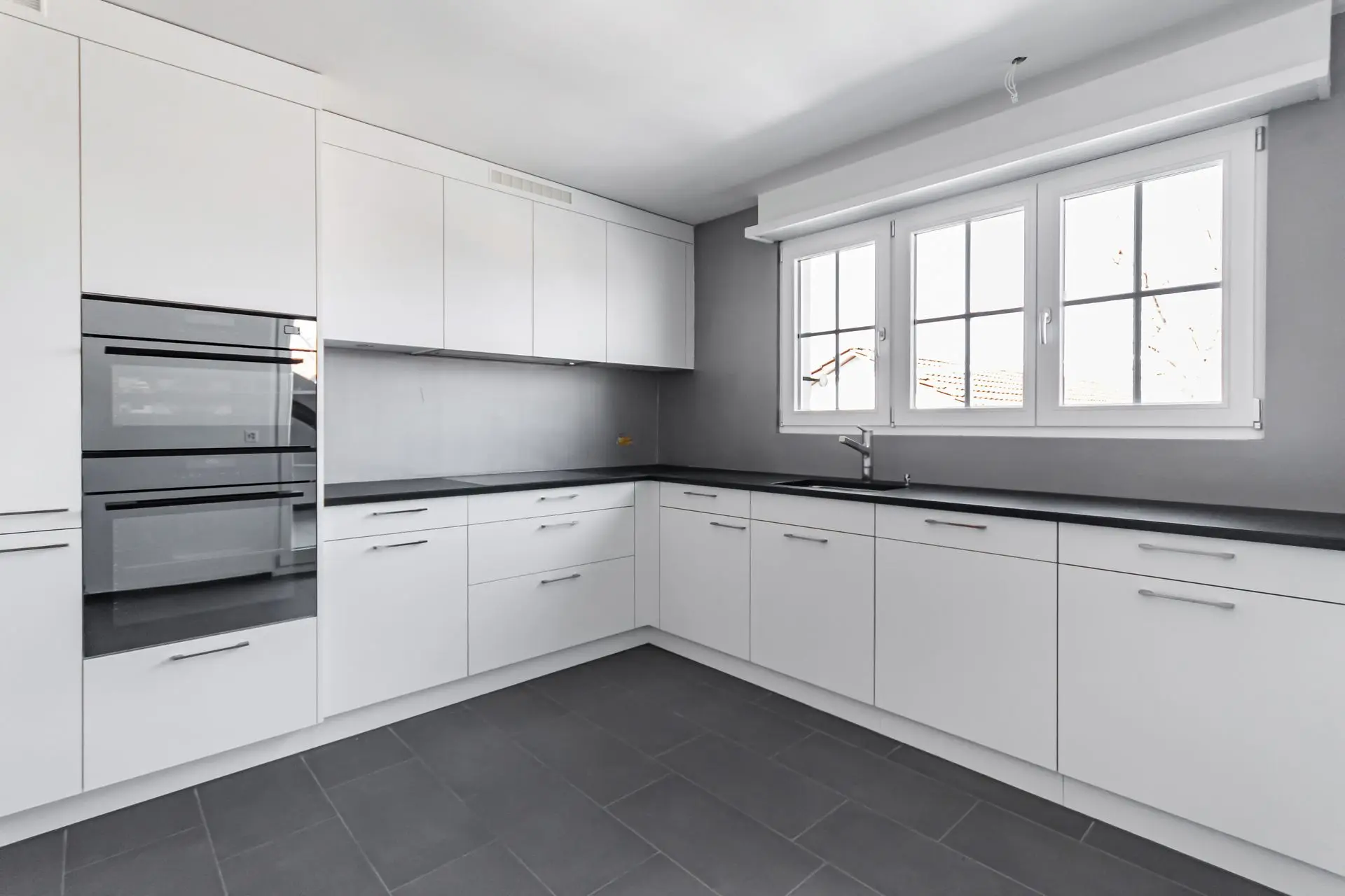 Bildoptimierung für Immobilienfoto – Küche mit weissen Fronten Optimiertes Foto einer modernen Küche mit weissen Schränken und grossem Fenster