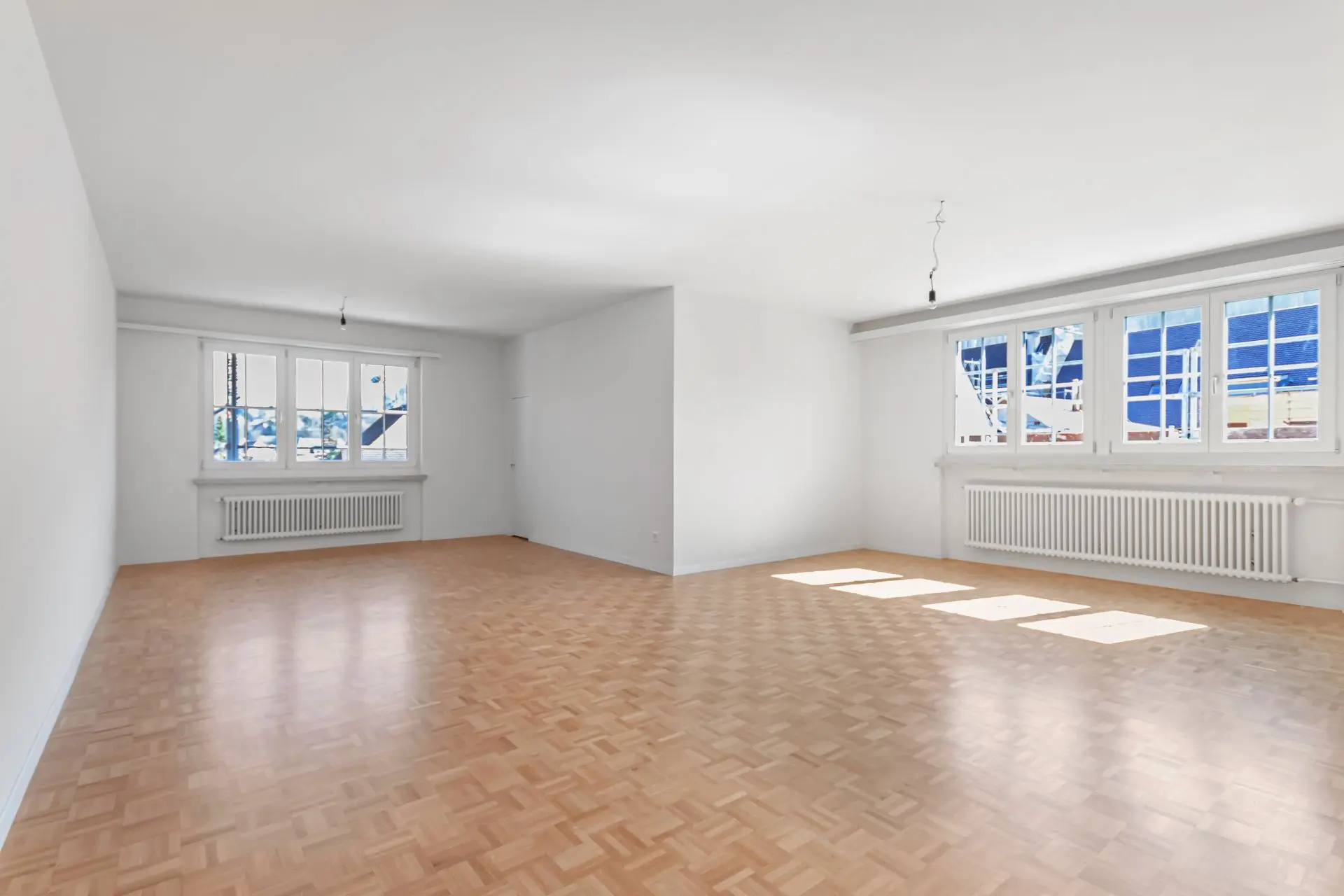 Bildoptimierung für Immobilienfoto – heller Wohnraum mit Parkettboden Optimiertes Foto eines leeren Wohnzimmers mit Parkettboden und grossem Fenster