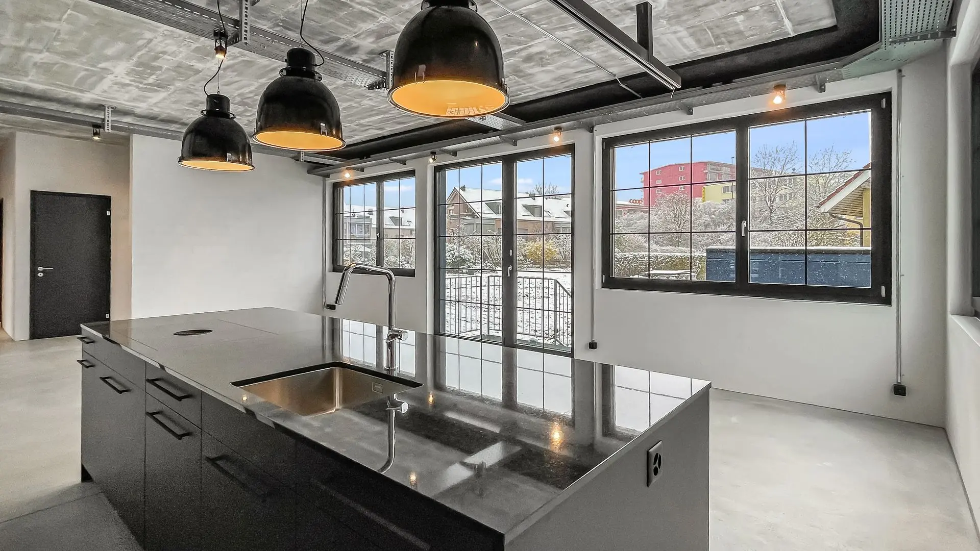 Bildoptimierung für Immobilienfoto – Moderne Küche mit Industrie-Design Optimiertes Foto einer Küche mit grossen Fenstern, schwarzen Fronten und Designlampen