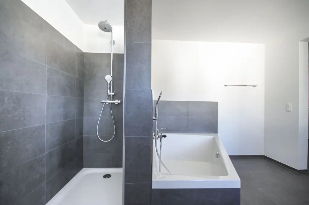 Hochwertig ausgestattetes Bad mit Dusche und Badewanne Modernes Badezimmer mit ebenerdiger Dusche und Badewanne in Grau-Weis-Optik