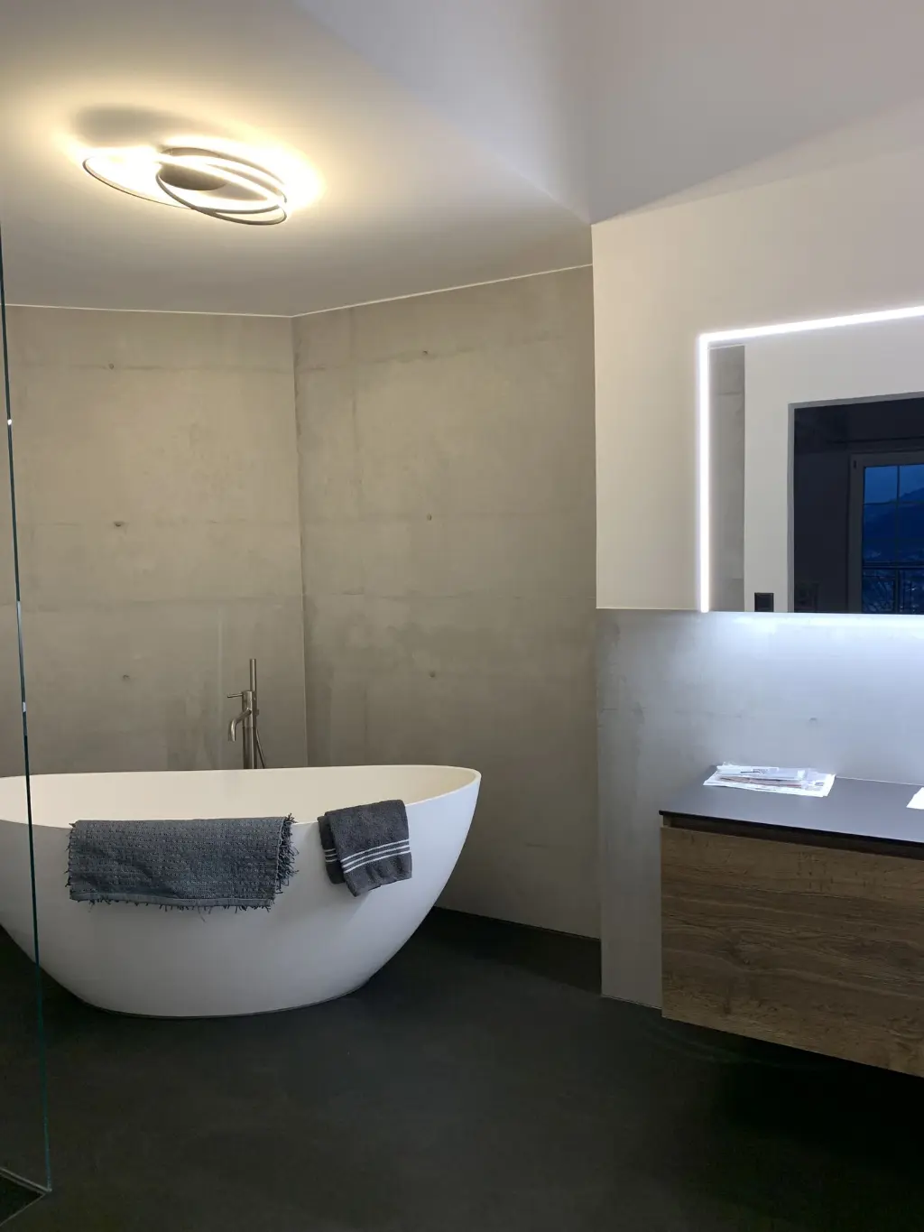 Modernes Bad mit funktionaler Ausstattung Badezimmer mit runder Deckenleuchte und grauen Fliesen