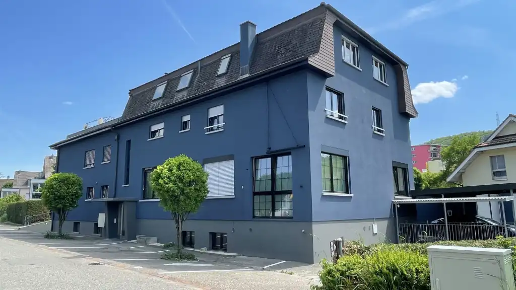 Freistehendes Haus mit zwei Wohneinheiten Zweifamilienhaus mit dunkelgrauer Fassade und gepflegtem Garten