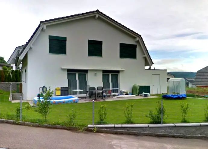 Einfaches weisses Einfamilienhaus mit grünem Fensterladen 