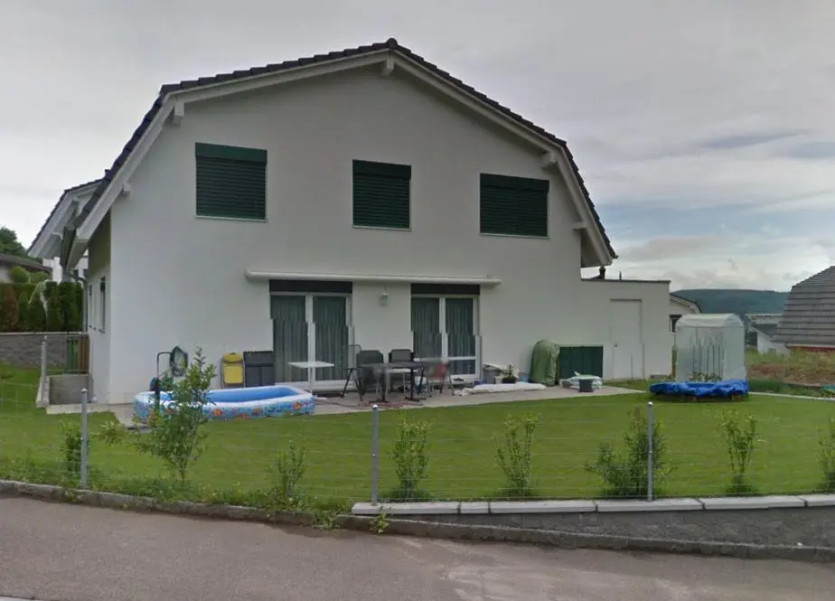 Einfaches weisses Einfamilienhaus mit grünem Fensterladen 
