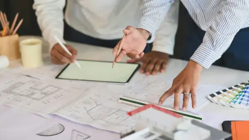 Zwei Personen arbeiten an Architekturplänen – Beginn der Konzeption und Umsetzung